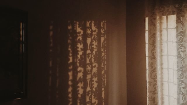 Luz do sol atravessando cortinas num quarto em penumbra