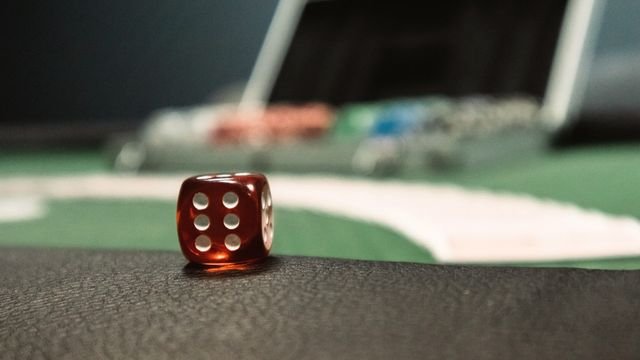 Um único dado vermelho sobre mesa de jogo em luz baixa