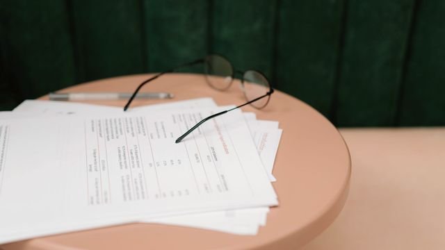 Formulários, caneta e óculos sobre uma mesa