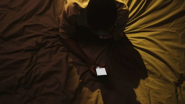 Pessoa deitada no escuro iluminada apenas pela tela do celular